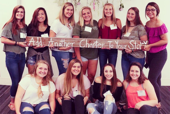 University of Nebraska Omaha sorority members holding a sign that reads add another chapter to your life.